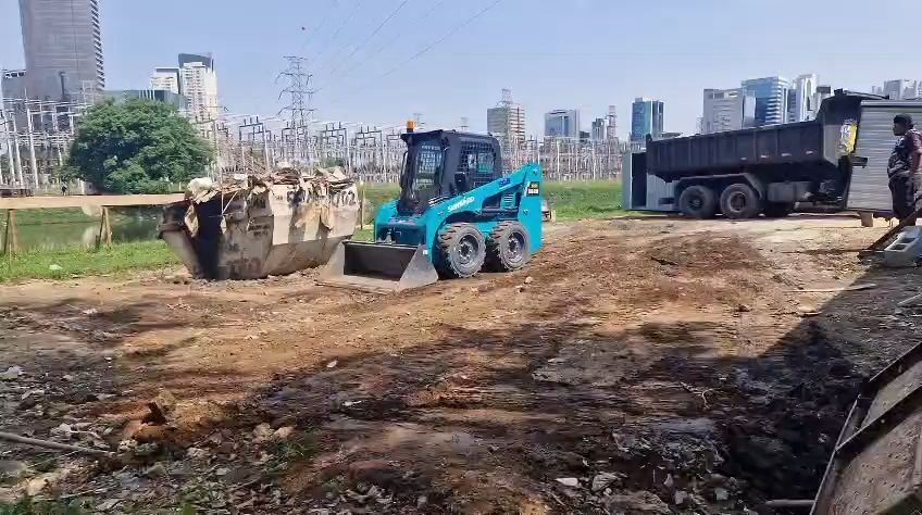 Minicarregadeira na limpeza do terreno, com caçamba e caminhão