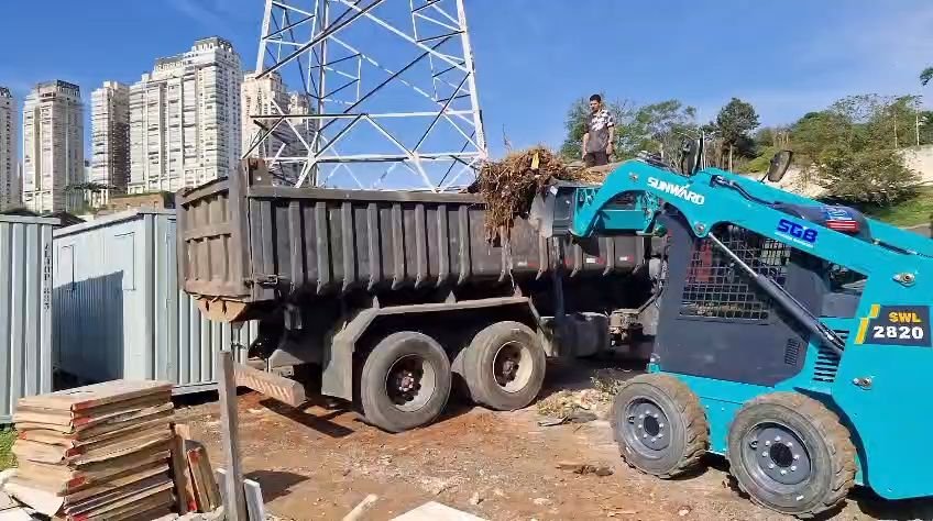 Minicarregadeira alimentando o caminhão basculante