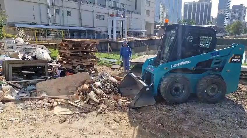 Minicarregadeira juntando resíduos para o carregamento